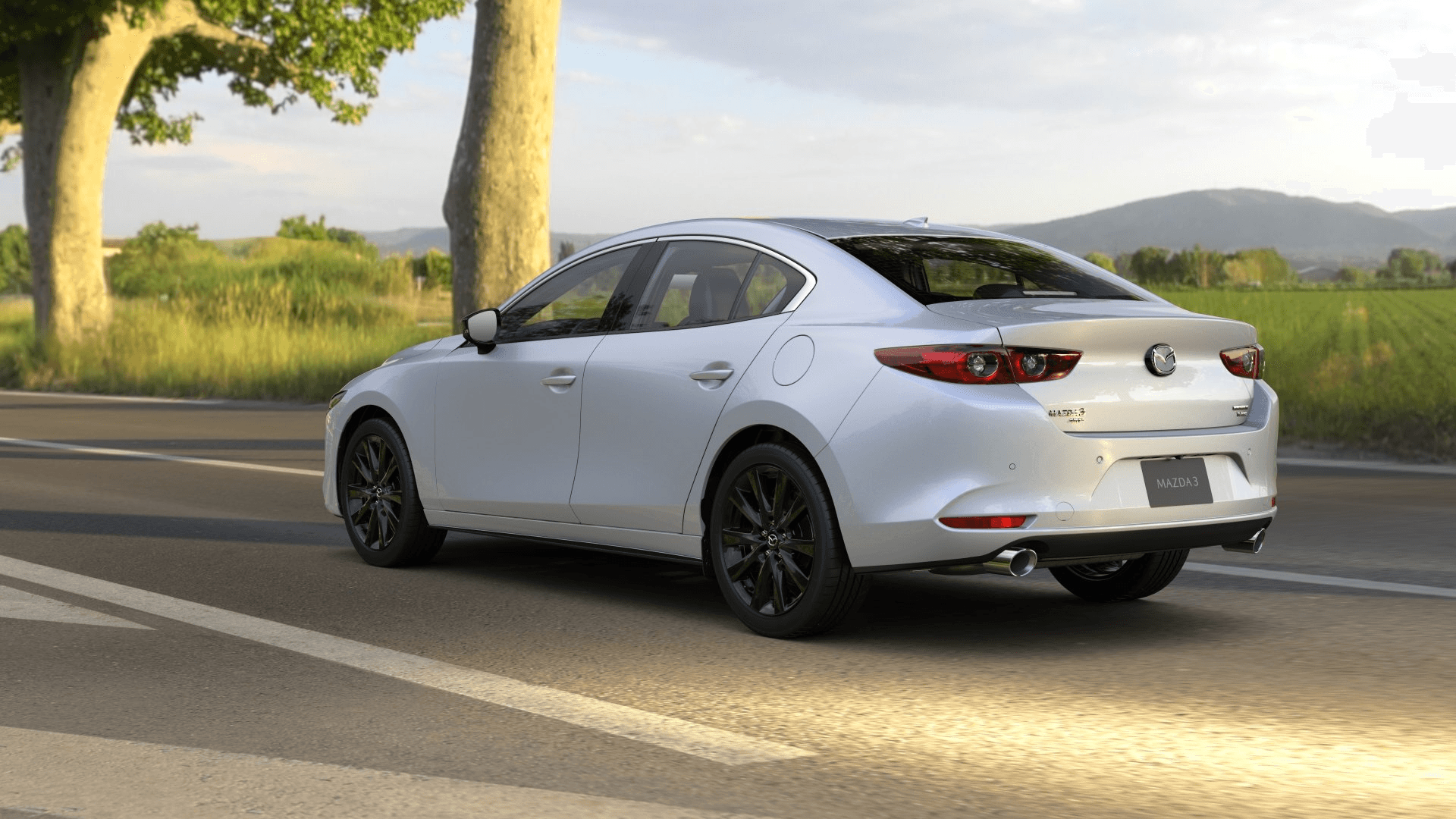 vue latérale arrière d'une Mazda 3 2025 sur une route de campagne