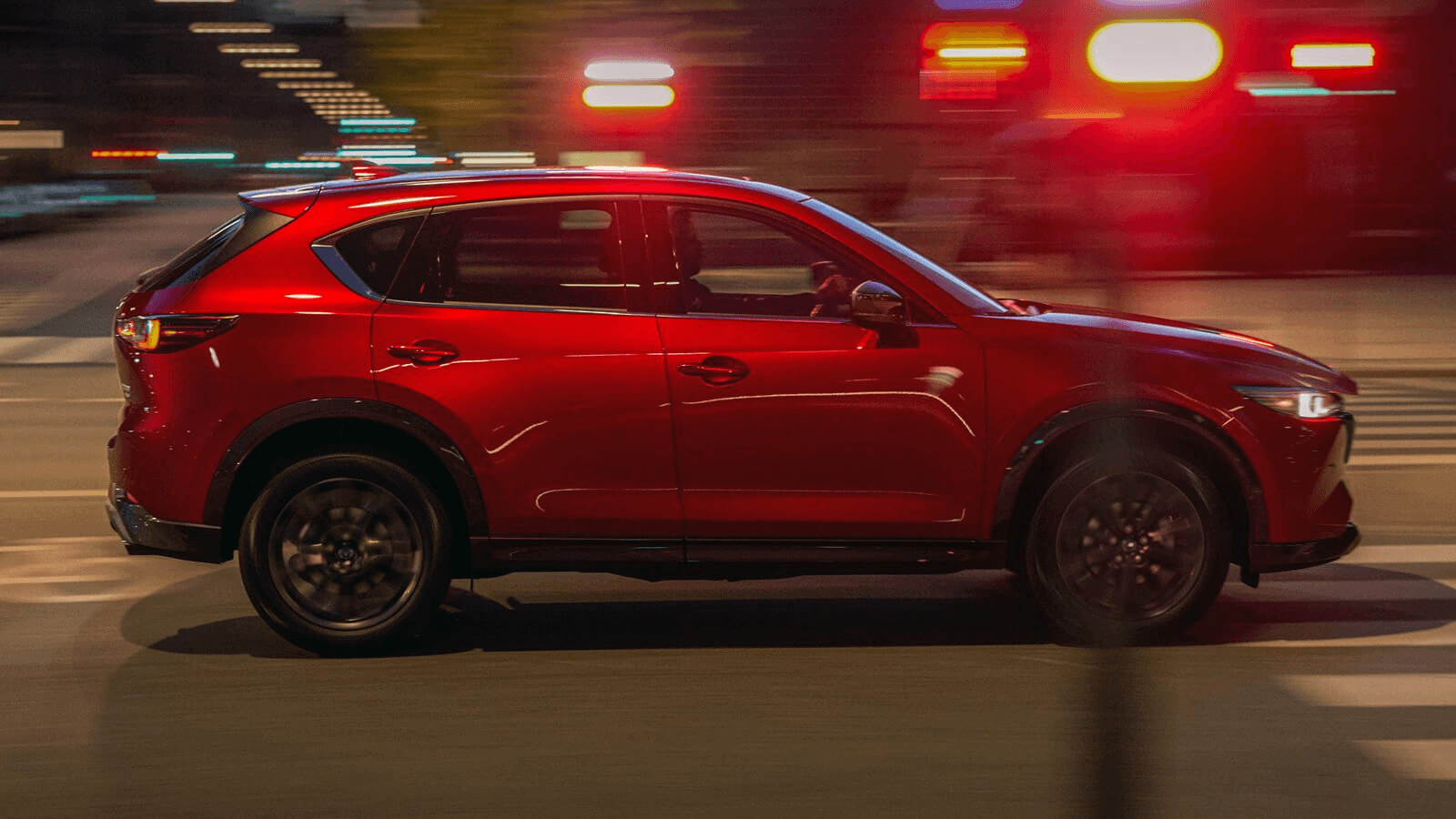 Le Mazda CX5 qui roule en ville la nuit.